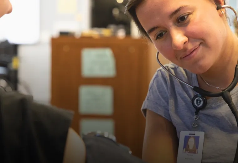 Student using a stethoscope to listen to the pulse of another individual.  