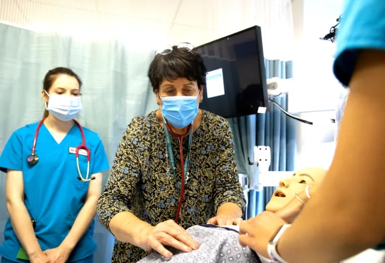 Three medical professionals working around a training dummy