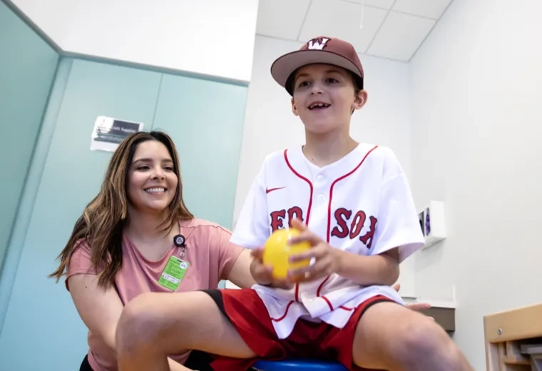 Medical professional smiling behind a child holding a ball