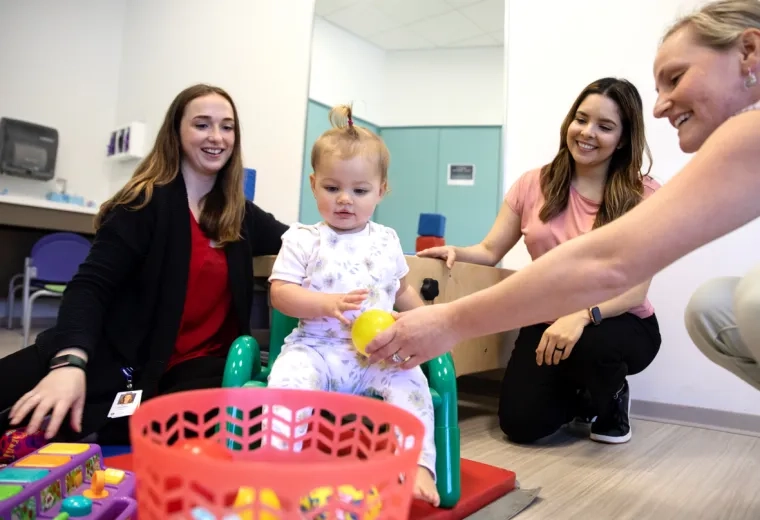 Several women playing games with a toddler 