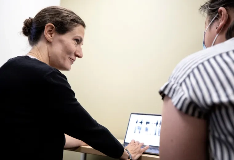 A woman smiling at a patient while she types on a laptop
