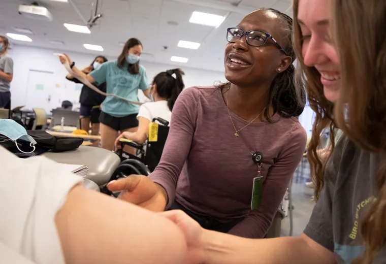 shot of classroom where students touch a patient knee together