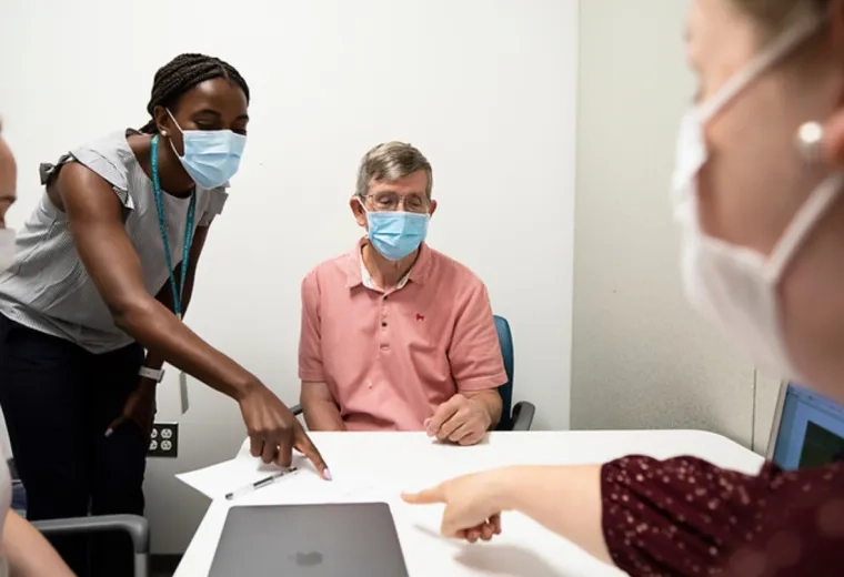 Two medical professionals pointing at a piece of paper while a patient observes 