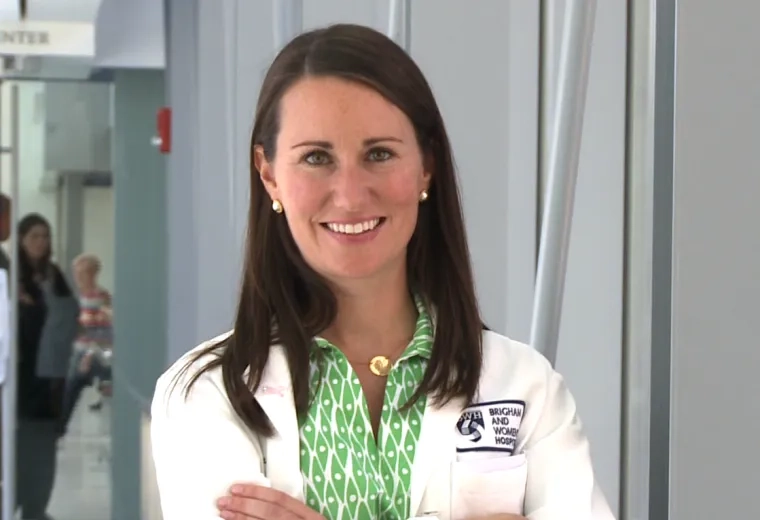 Bridget stands with her arms folded with a smile