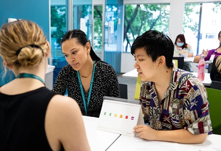 Three individuals engaging in discussion around evidence-based literacy instruction techniques.