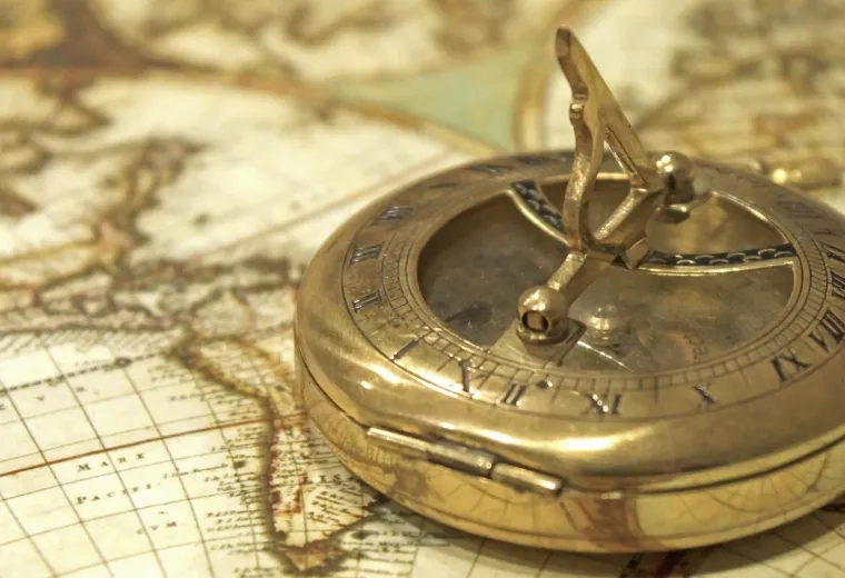 a golden compass sits on an antique sepia toned map