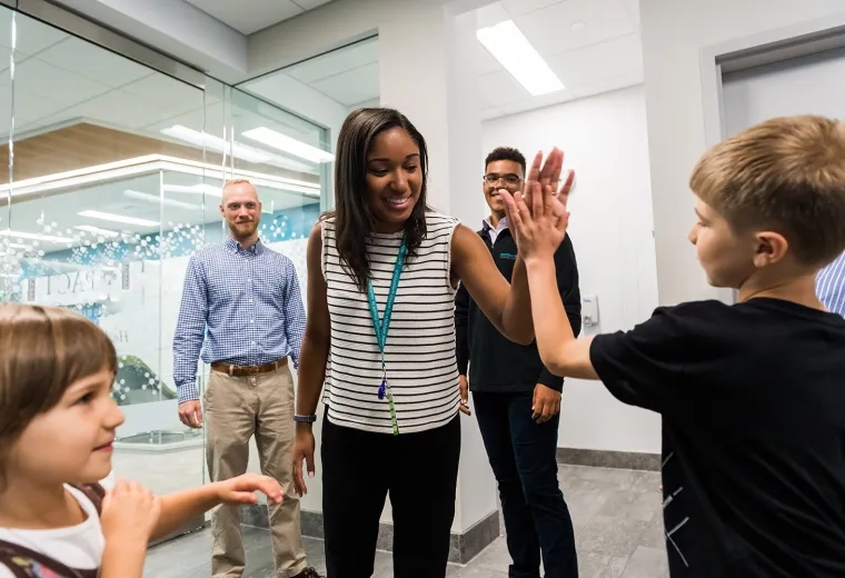 woman gives high five to child in hallway