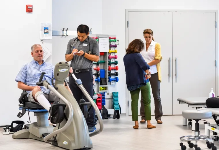 Medical professionals with patients inside a room with dumbbells' and stationary bikes