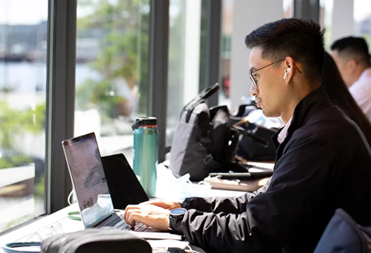 Male student at laptop in front of a window