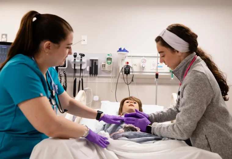 Two nurses practicing on a training manikin