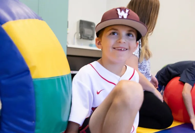 A young boy smiling while wearing a baseball hat