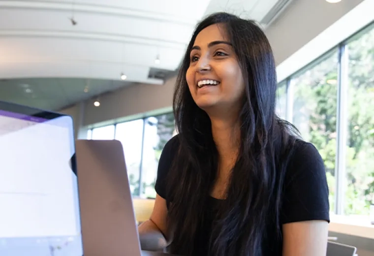 Woman smiles over laptop in study group