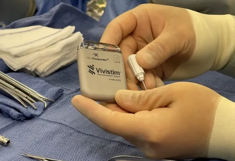 gloved hands hold a grey rectangular device over sterile surgical towel