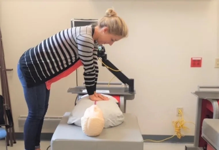 woman performs chest compressions on a manikin