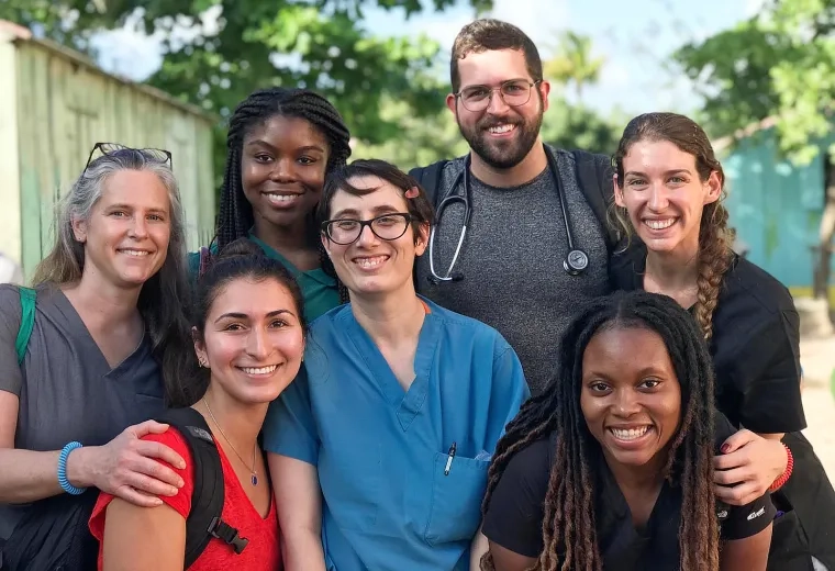a group of smiling people stand in the street, one wears a stethoscope 