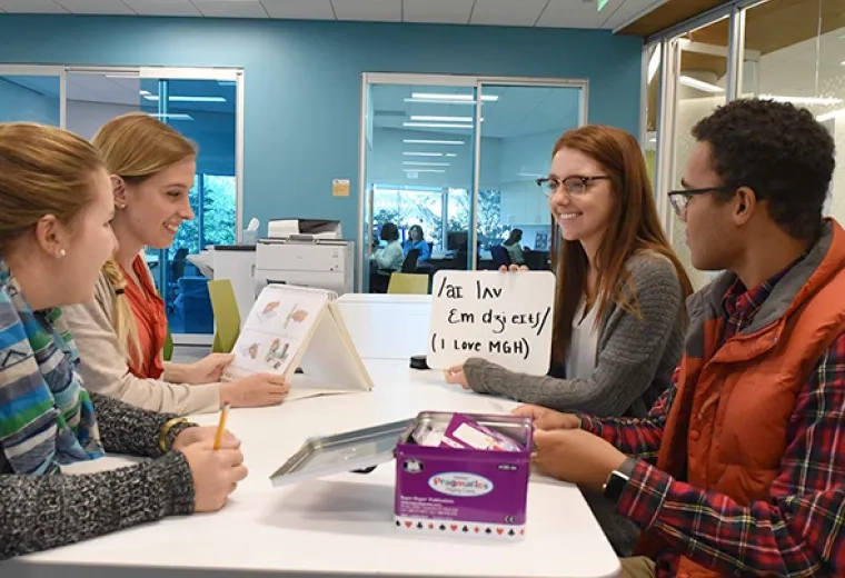 4 students sit at a table and look at words on a card