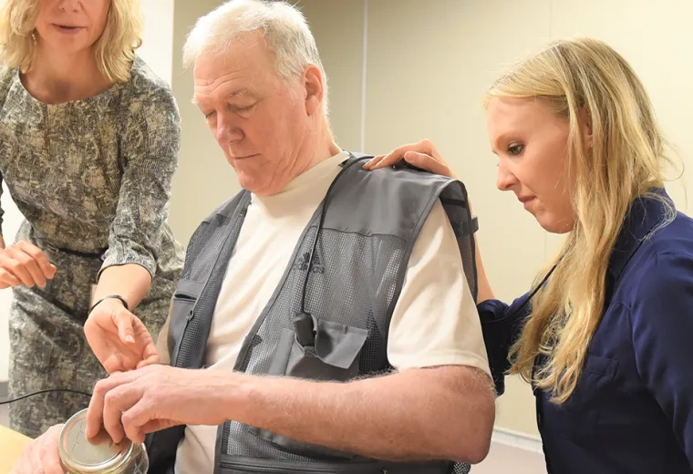 Photo of Dr. Teresa Kimberley (left) works with a patient (center) and a grad assistant at the Brain Recovery Lab on the MGH Institute campus.