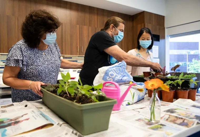 man digs in a planter to plant a plan with help from staff