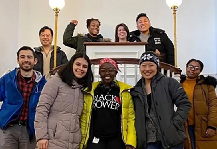 Photo of multiple people standing around a podium. 
