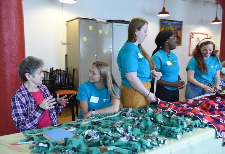 students smile and chat while at a table with fleece blankets