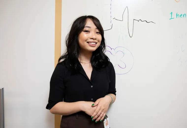 student smiles in lab in front of white board