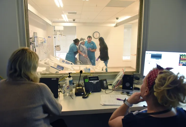 faculty observe nursing students with standardized patient through glass