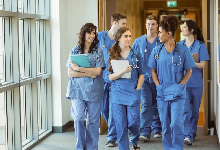 a group of people walk down a hallway in scrubs
