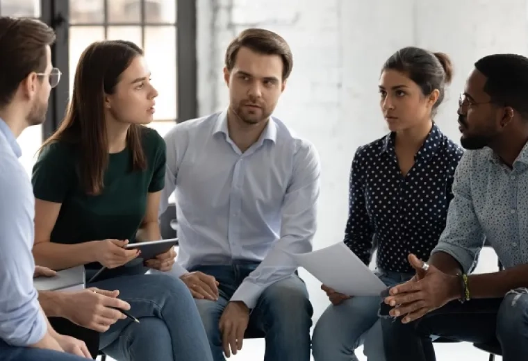 group of people with stern faces speak in a circle to each other