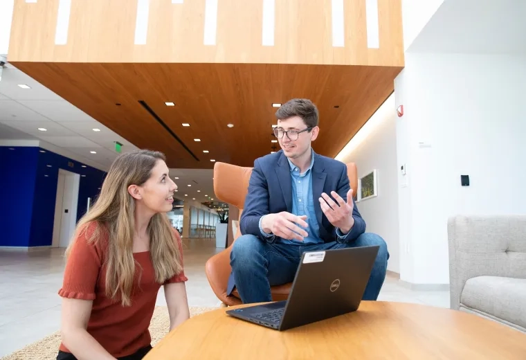 A man and a woman sitting in front of a laptop having a discussion
