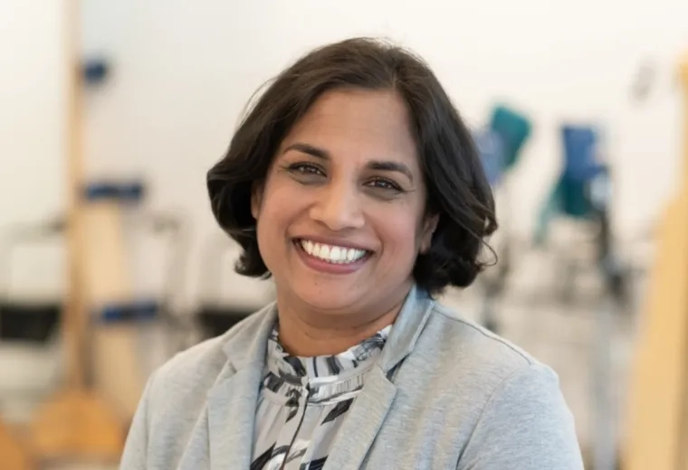Professional portrait of an MGH IHP Doctor of Physical Therapy faculty member with a clinical setting in the background