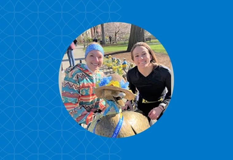 two women in running gear smile near the boston ducklings statue