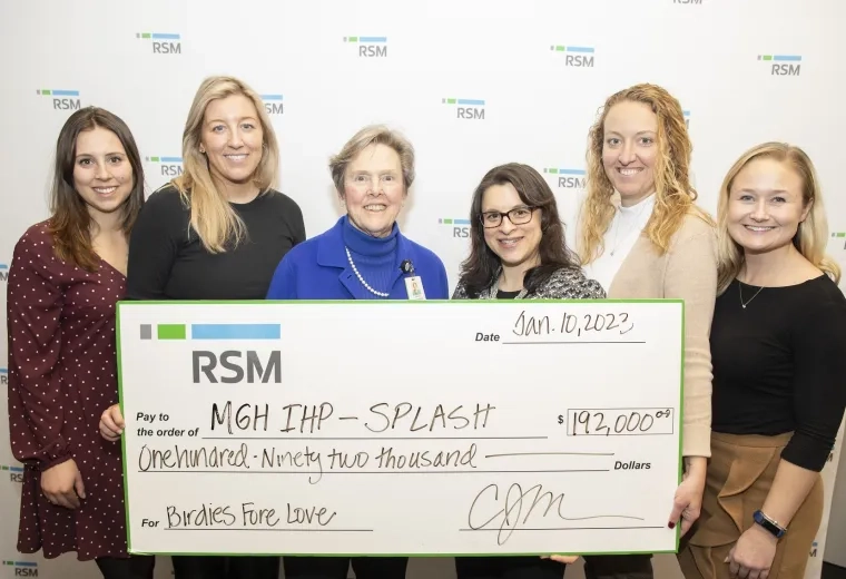 a group stands holding a check that says RSM, MGH IHP Splash $192,000