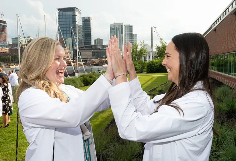 woman in white coat gives double high five to other woman in white coat