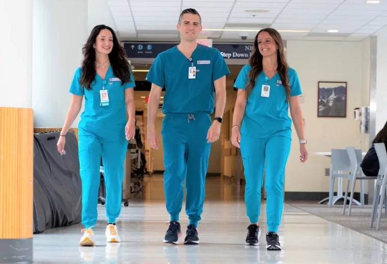 Three nursing students in scrubs walking in  MGH corridor