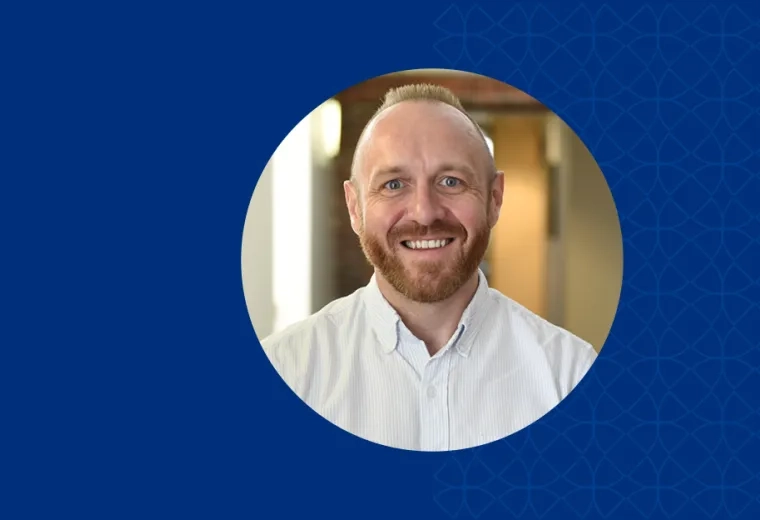 brad has a reddish brown beard and mustache and wears a white collared shirt