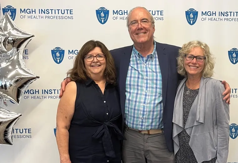 charley stands with his arms around the two ladies next to some silver balloons