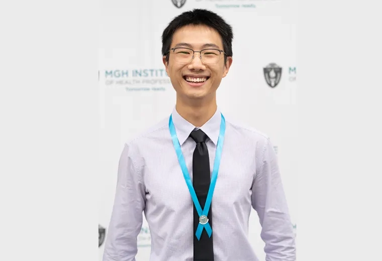 Asian man with black hair and glasses wears a black tie and off white collared shirt with a teal ribbon around his neck
