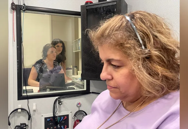 Woman with headphones in room with two people observing through a window