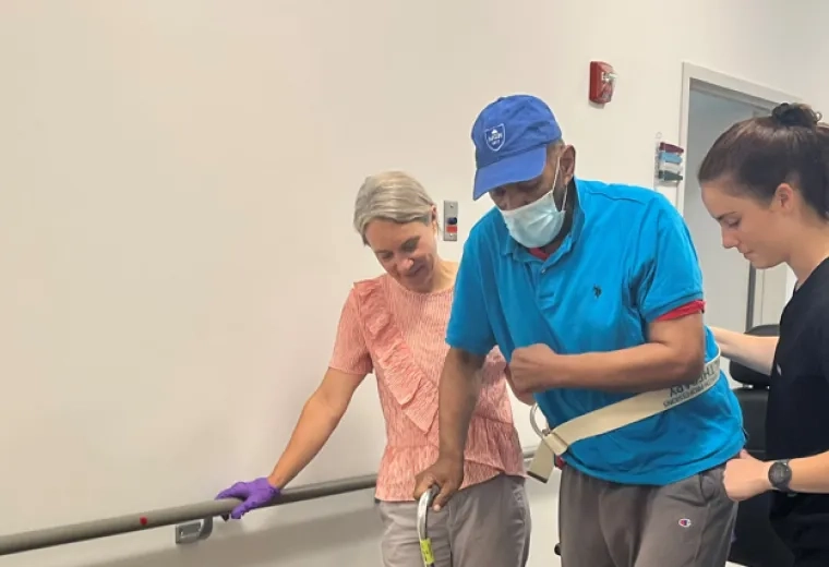 Man walks with cane and two physical therapists