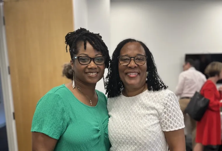 Two women stand and smile
