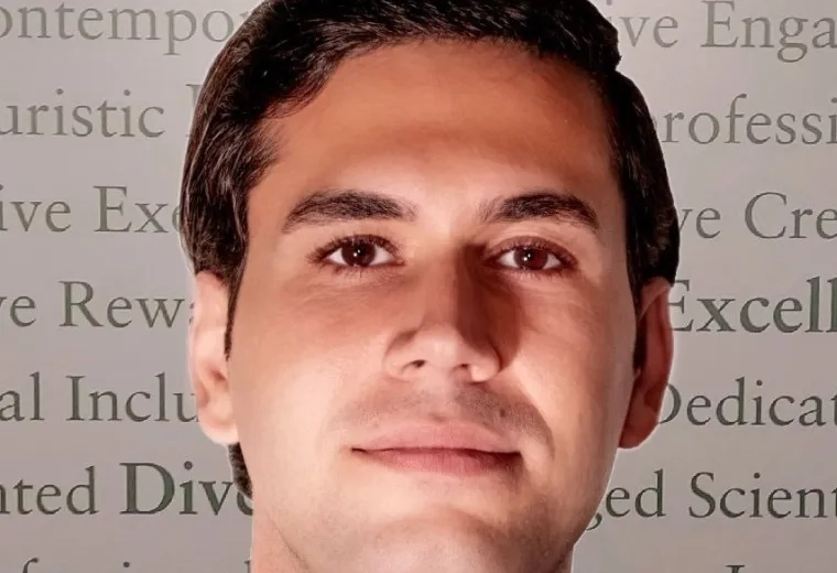 ehsan is lit from below and wears a tie and sweater over a white collared shirt