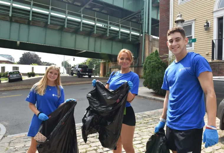 Three students hold trash bags under the Tobin