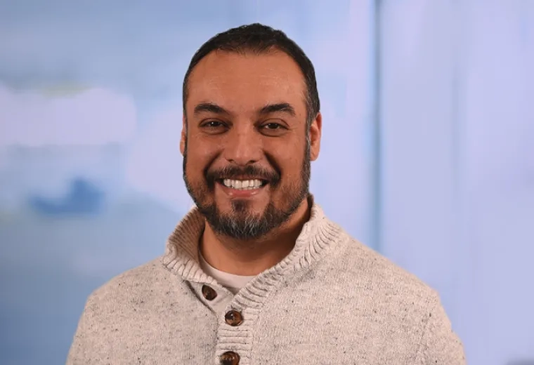 jorge has a cream colored sweater on with brown buttons