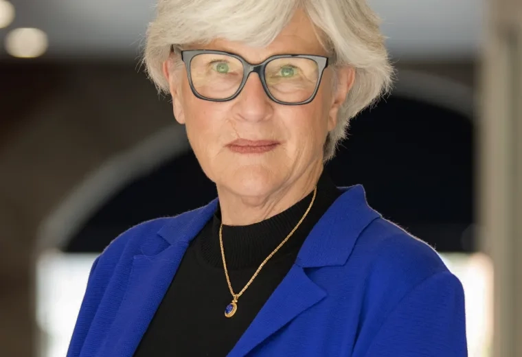 suzie has a blue blazer and black shirt on with short grey hair