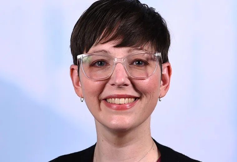 kathryn has clear framed glasses and very short brown hair