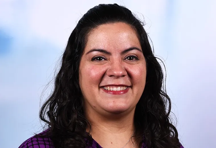 Headshot of a faculty member in the MGH IHP Doctor of Speech-Language Pathology program - she has wavy dark hair and wears a purple and black patterned top