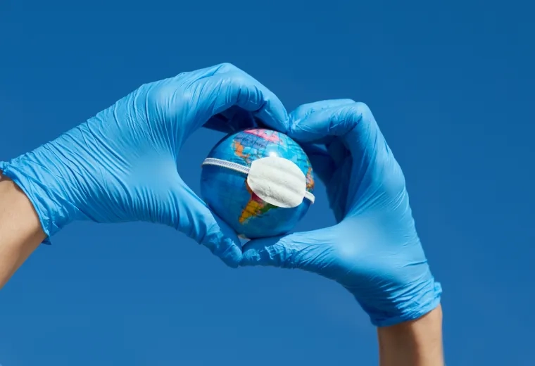 blue surgical gloved hands with masked model of the earth