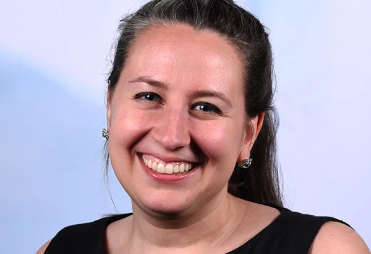 megan has her hair in a braid and wears a sleeveless black shirt