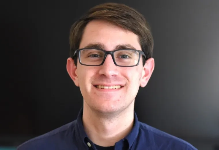 jeremy wears a navy button up and has black rectangular glasses