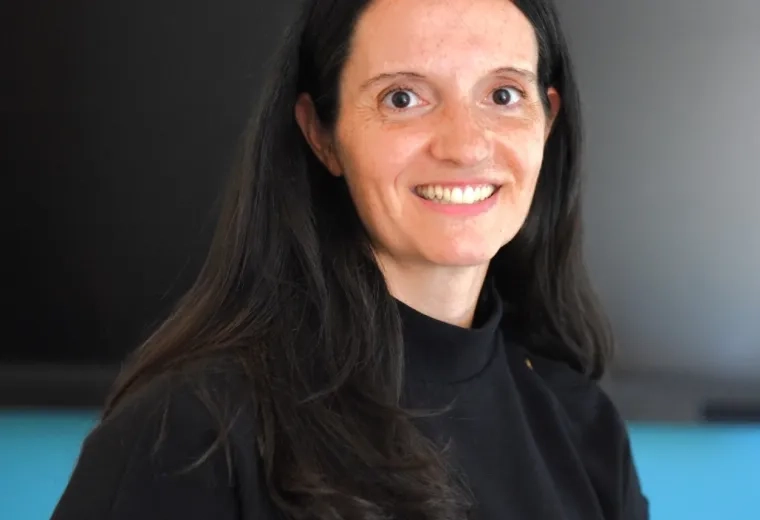 Katey has long dark hair and wears a black short sleeved top